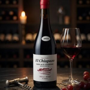 Botella de Vino El Chispazo 2024 junto a una copa de vino tinto en una bodega con uvas y sacacorchos.